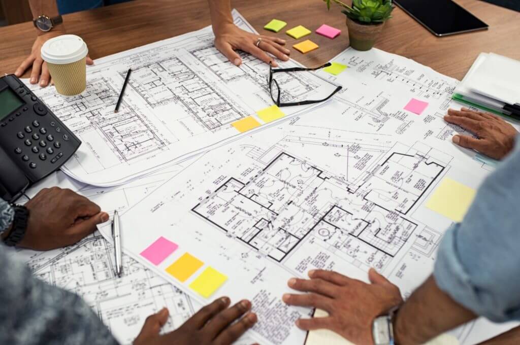 Closeup,Of,Multiethnic,Hands,On,Blueprints,At,Architects,Office.,Team